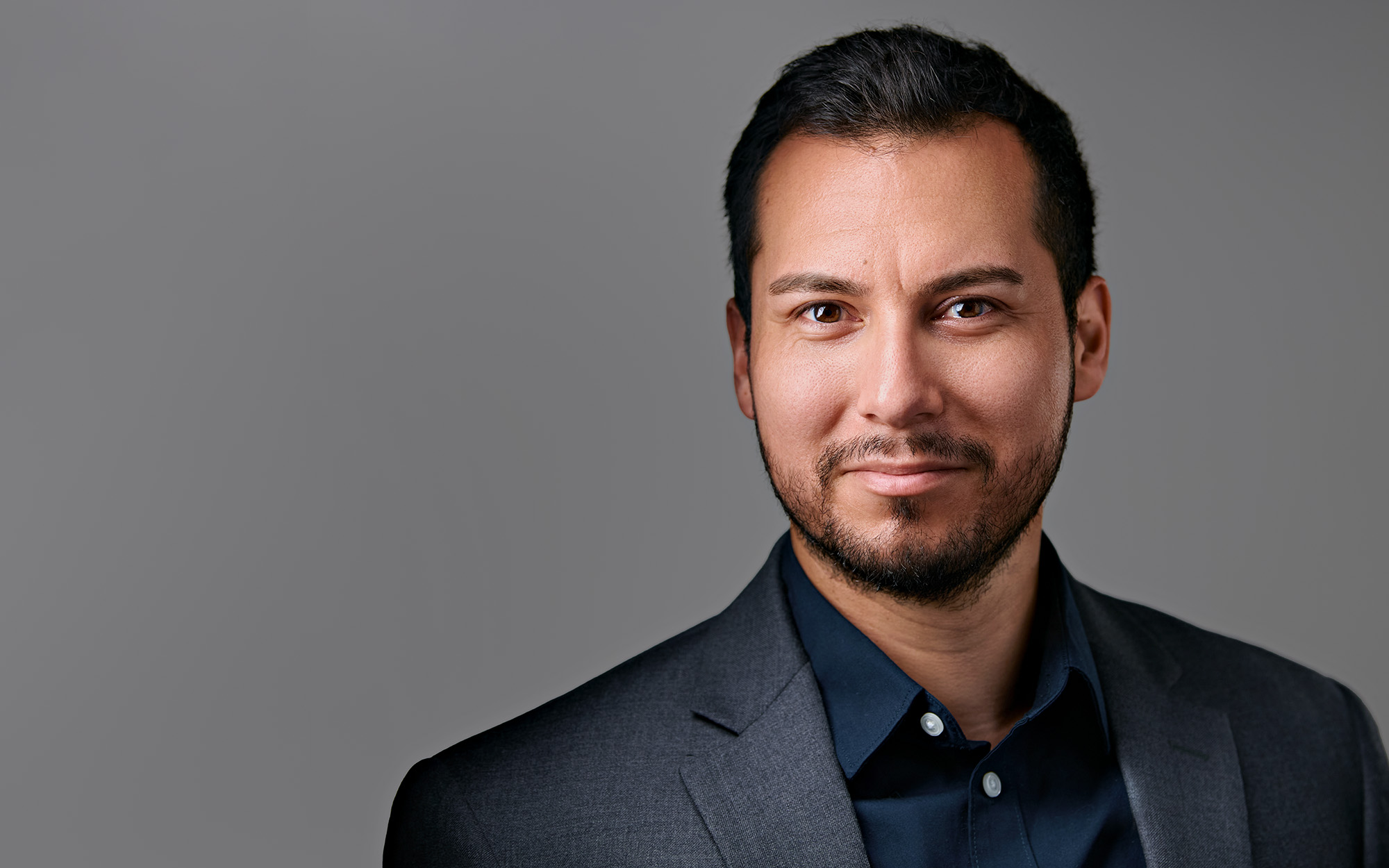 Professional Headshot — Palo Alto, CA Professional headshot of a man in a dark suit, on a gray background.