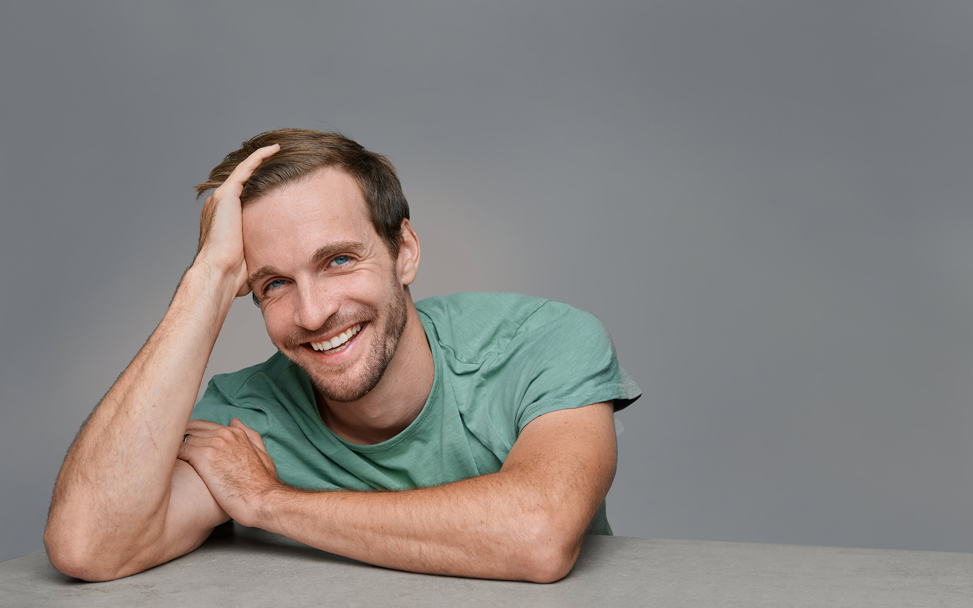Modern Studio Portrait — Palo Alto Studio portrait of a man in a green shirt, smiling, against a gray background.