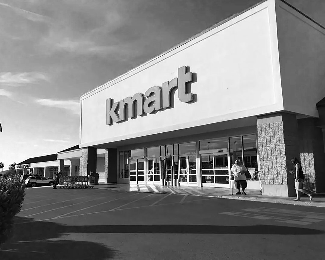 A black and white photo of the entrance to a Kmart department store.