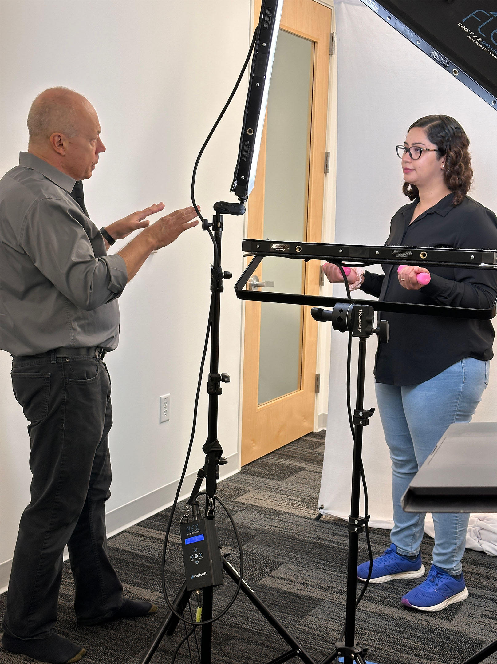 This image captures Dean Birinyi coaching a female client during a corporate headshot session in Santa Clara. The setup emphasizes professional lighting and a collaborative approach to ensure the client’s confidence and best expression are reflected in the final images.