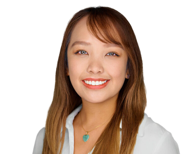 Corporate headshot of a female executive in Palo Alto by Dean Birinyi, featuring a confident smile, light blue blouse, and gold necklace against a clean white background.
