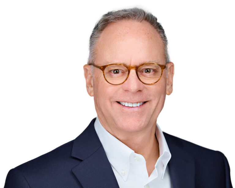 Corporate headshot of a male CEO in Palo Alto by Dean Birinyi, featuring a confident smile, glasses, and a navy blazer against a clean white background.