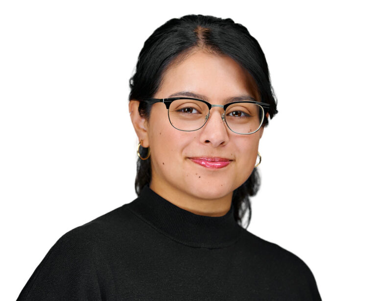 Corporate headshot of a female product manager in Palo Alto by Dean Birinyi, featuring a composed expression, glasses, and a black top against a clean white background.