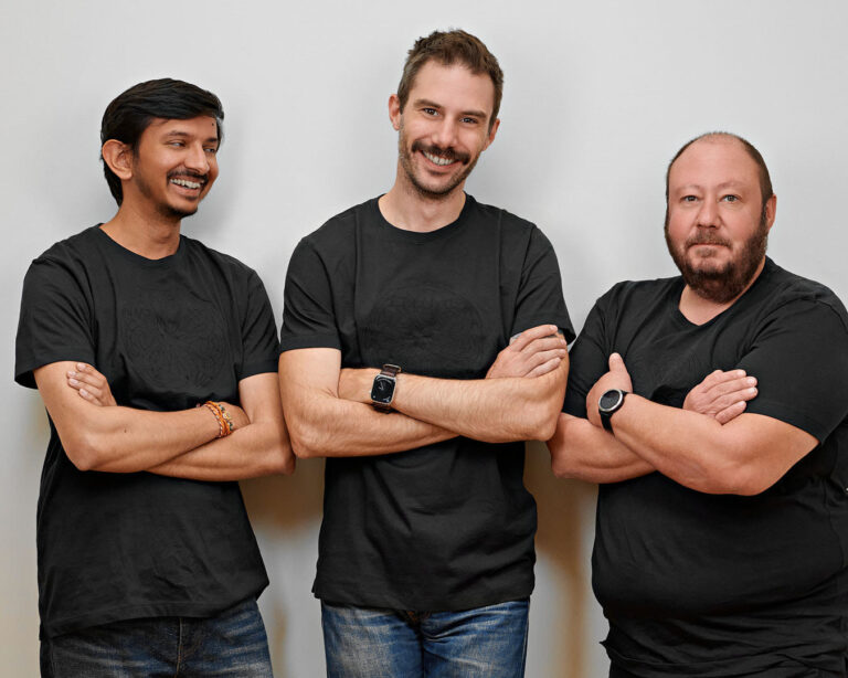 Team photo of startup engineers wearing casual black T-shirts and jeans, smiling confidently in a Silicon Valley office environment, showcasing camaraderie and innovation.