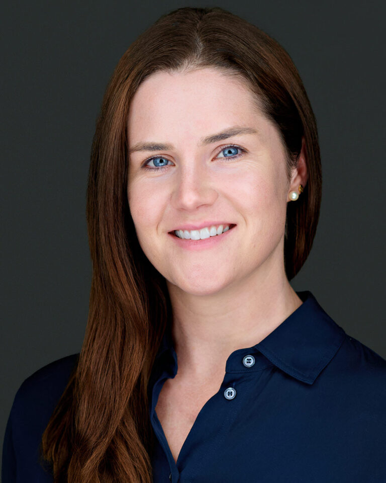 Professional headshot of a marketing and communications expert with a poised and confident expression, set against a dark gradient background in Santa Clara. Ideal for showcasing expertise in strategic branding and corporate communication.