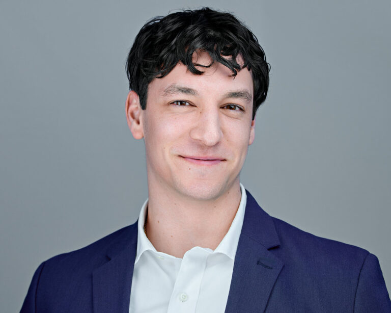 rofessional headshot of a confident man in a dark blue suit and white shirt, photographed by Dean Birinyi in Palo Alto for a Silicon Valley company’s download system.