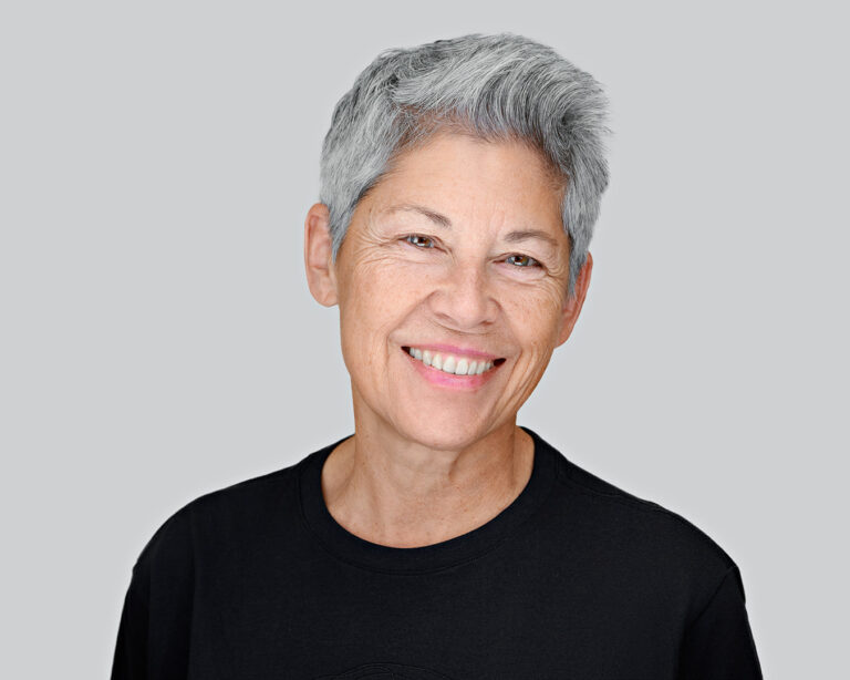 Smiling woman with short gray hair in a black shirt, photographed by Dean Birinyi for a company headshot session in Palo Alto.