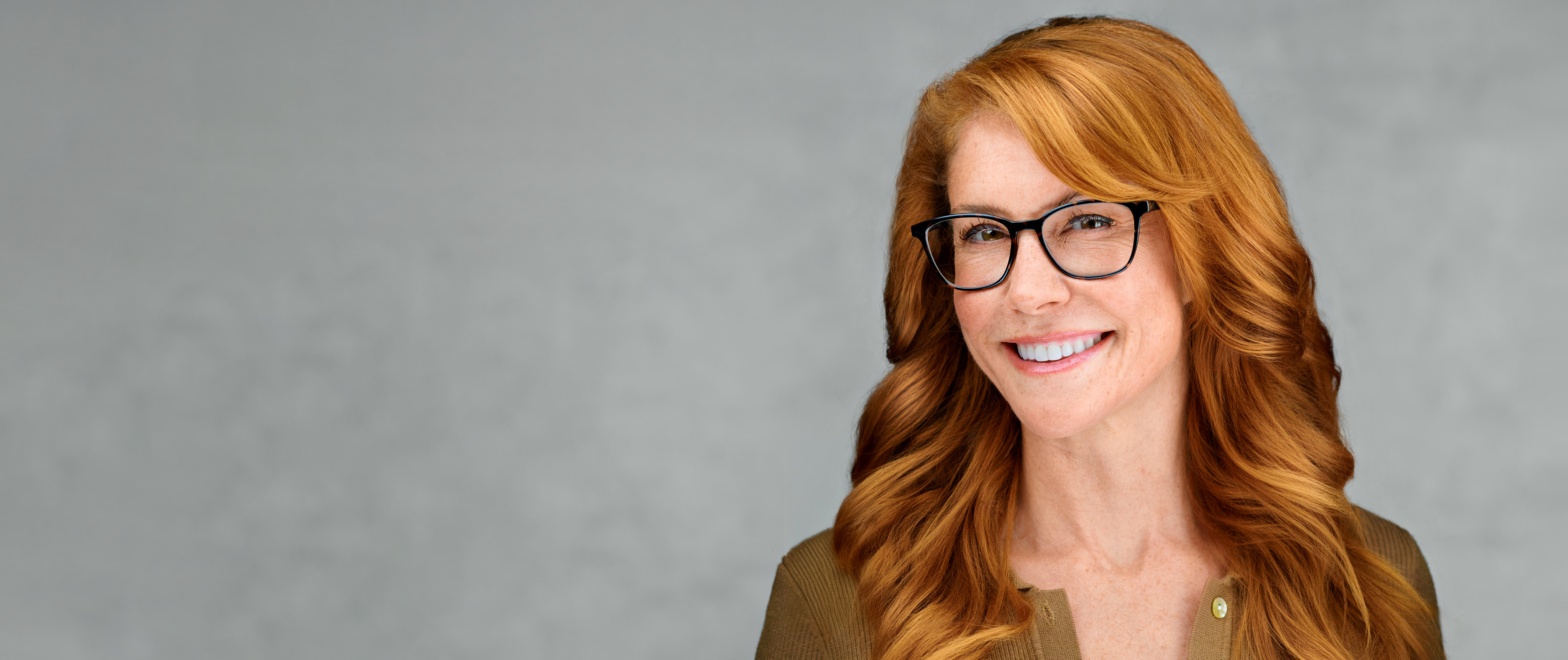 Professional headshot of a smiling woman with red hair and glasses, photographed by Dean Birinyi in Palo Alto.