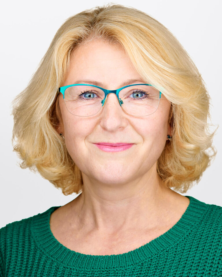 Corporate headshot of a Stanford biotech executive photographed by Dean Birinyi, featuring a confident smile, glasses, and a clean white background.