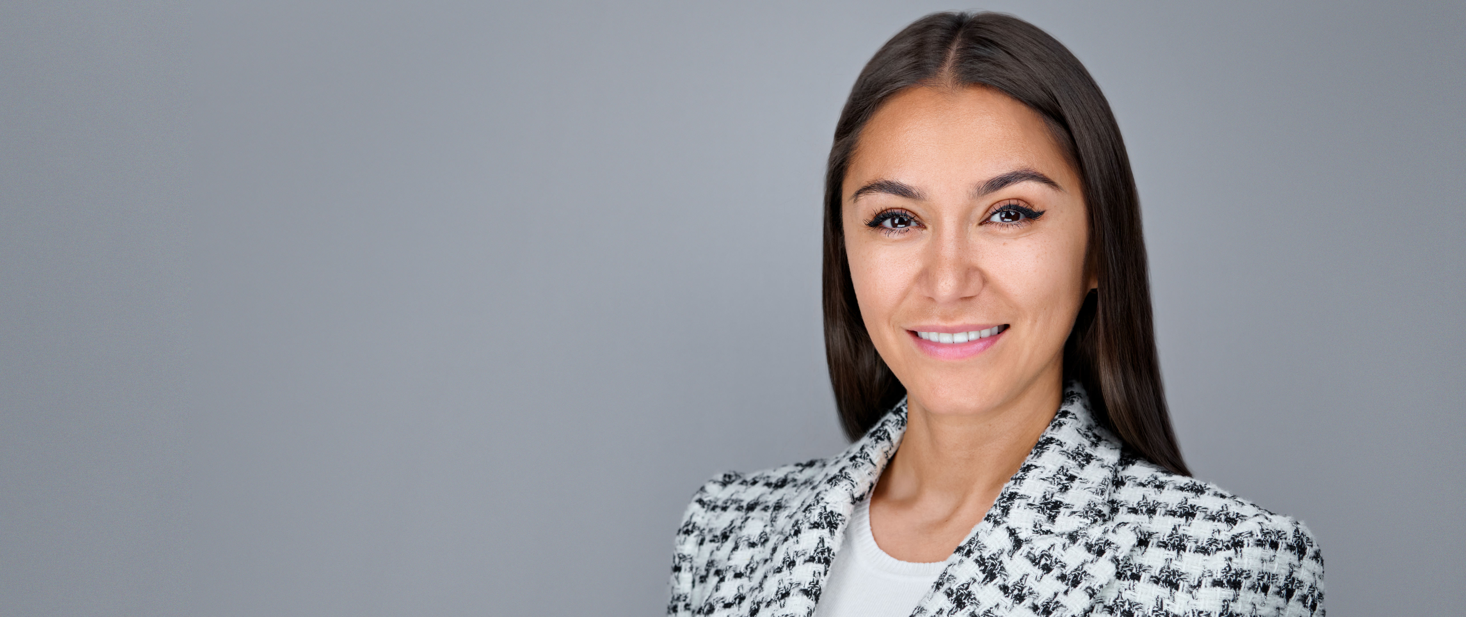 This widescreen-format headshot features a Redwood City professional photographed in studio by Dean Birinyi. The subject is positioned against a seamless gray background with ample negative space to accommodate banner placement, ideal for desktop viewing. The image was composed with brand consistency and responsive display in mind, reflecting the high production standards offered to Redwood City companies seeking clean, confident, and leadership-ready corporate headshots.