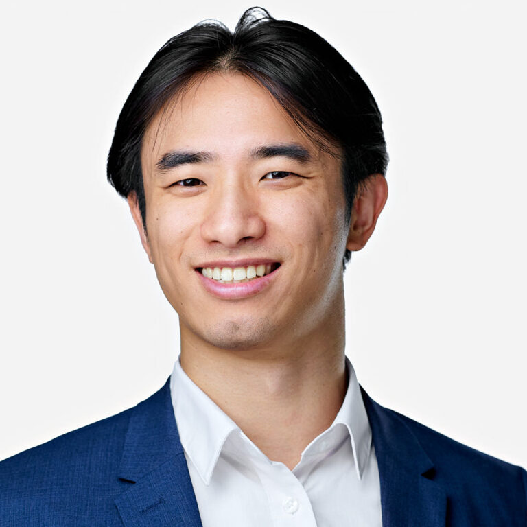 Studio headshot of a man in blue jacket, white background.