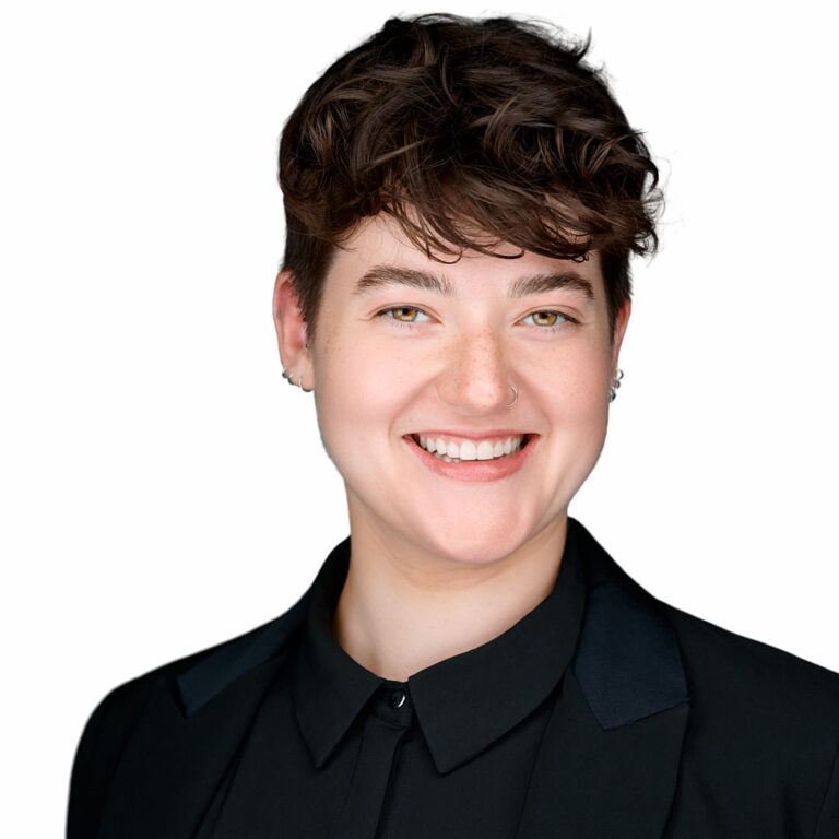 Studio headshot of a smiling person with short hair and black jacket.