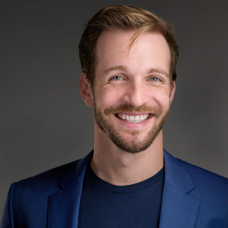 Professional headshot of a smiling man in a blue blazer and dark shirt, photographed by Dean Birinyi in Palo Alto.