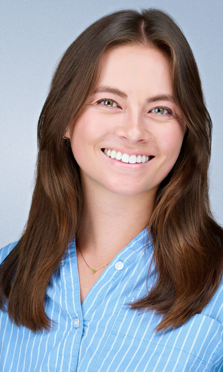 Professional corporate headshot of a smiling woman wearing a light blue striped shirt, photographed by Dean Birinyi Photography in Santa Clara, California. Image featured on the company headshot system page to illustrate approachable, consistent portraits for Bay Area professionals.