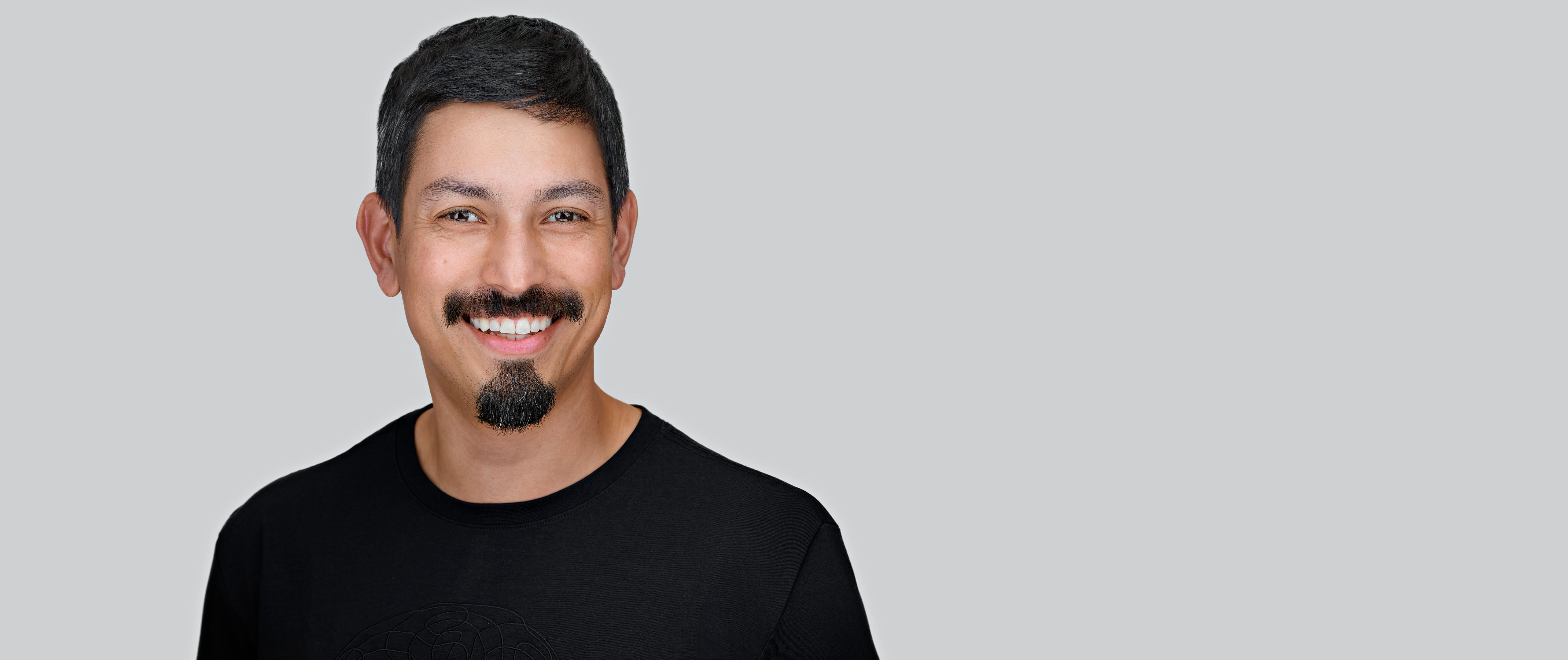 Professional corporate headshot of a smiling executive on a neutral gray background, showing polished lighting and expression consistent with brand-aligned company portraits.