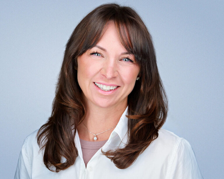 Professional headshot of a woman smiling against a light gray background.