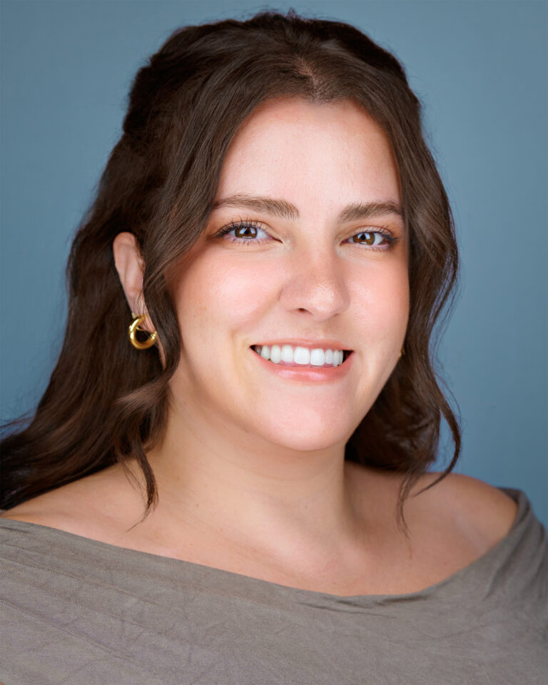 Professional headshot of a woman smiling against a soft blue background, used as a testimonial banner for corporate headshot services in Palo Alto and the Silicon Valley area.