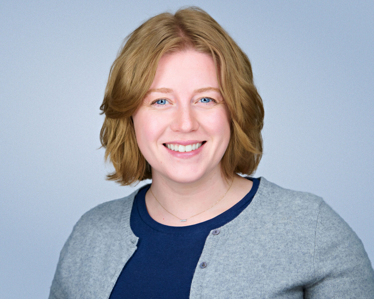 Professional headshot of a smiling woman photographed in Santa Clara with soft studio lighting and a clean light-gray background.