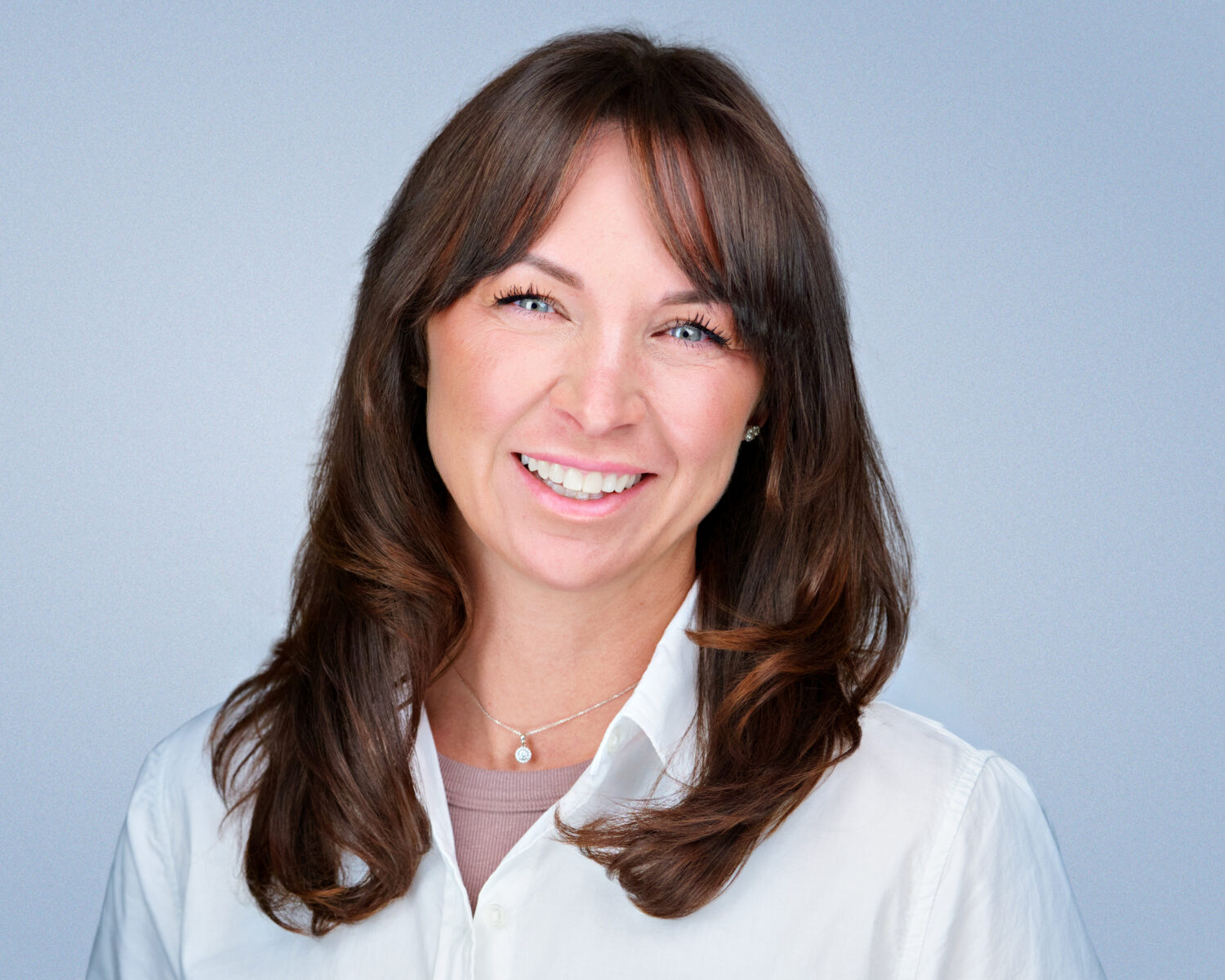 Professional headshot of a smiling woman photographed in Silicon Valley with soft studio lighting and a clean light-gray background.