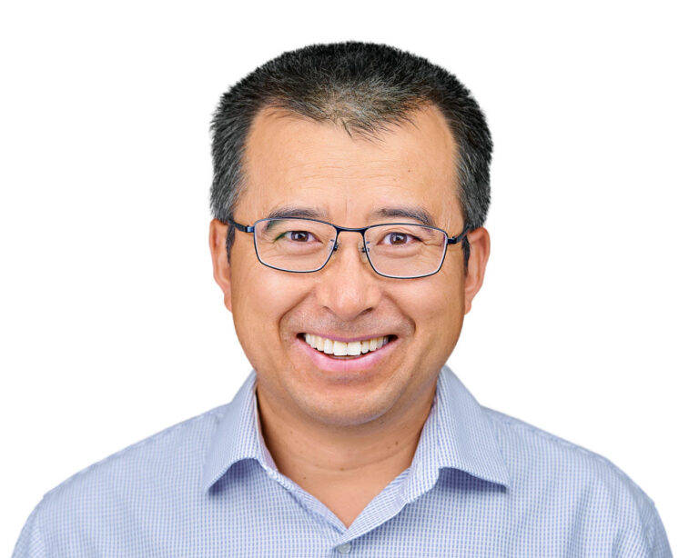 Professional corporate headshot of a smiling executive on a white background