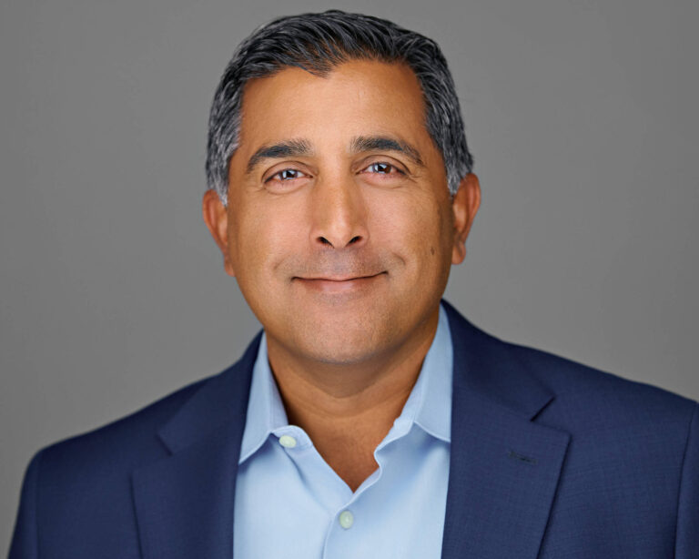 Corporate headshot of a male executive in blue blazer, photographed on-site in San Mateo, California.