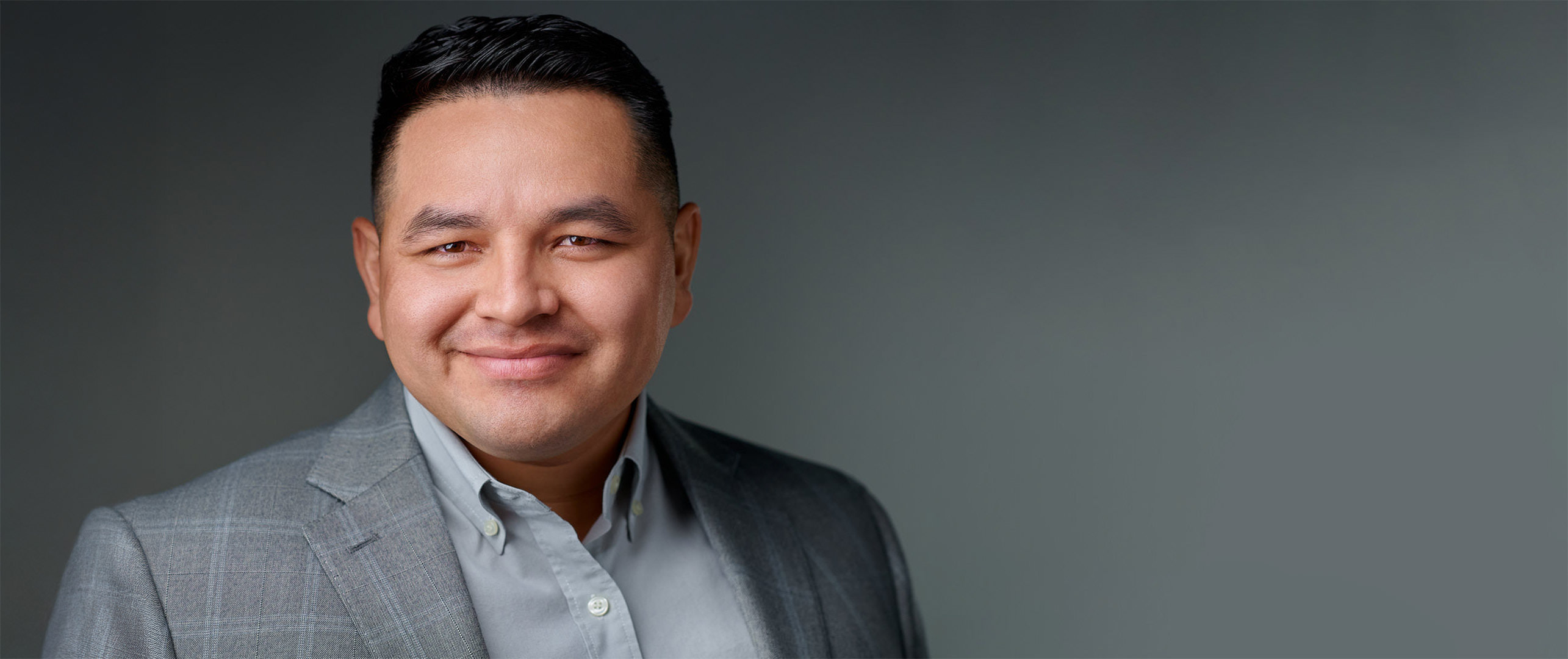 Corporate headshot of a male executive in a gray jacket, photographed on location in San Mateo, California.