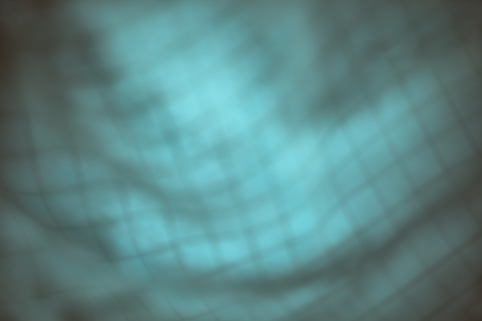 Abstract photograph of a softly blurred turquoise-blue field with faint darker lines and translucent curved forms emerging across the center and lower portion of the frame.