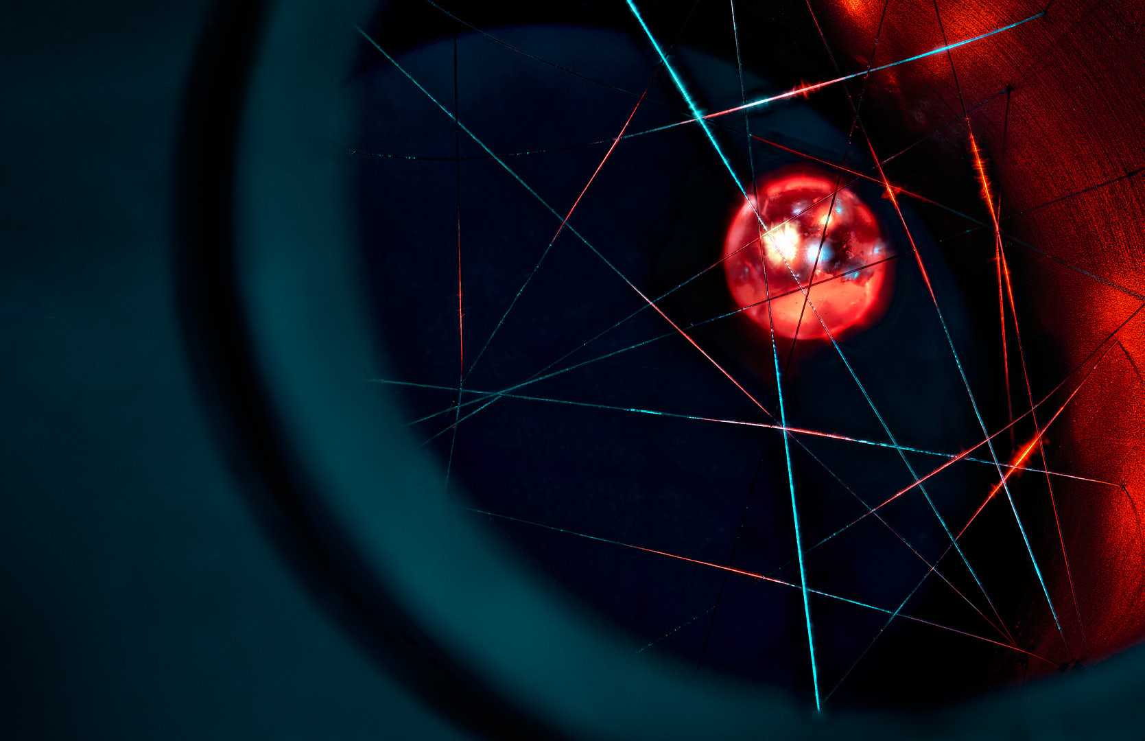 Abstract photograph of a glowing red circular form near center-right, crossed by intersecting red, cyan, and dark lines, within deep blue and black curved shapes.