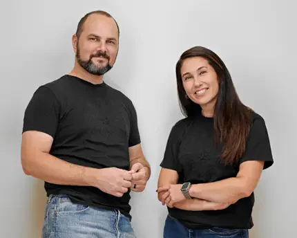 Startup in-house counsel and HR director in casual black T-shirts and jeans, standing together in a Bay Area office, smiling confidently to reflect professionalism and approachability.