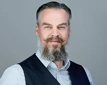 Bearded man with styled mustache in vest and striped shirt, photographed by Dean Birinyi for a professional company headshot in Silicon Valley.